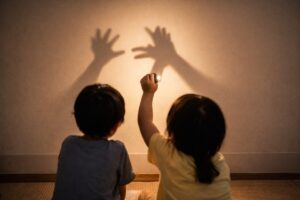 室内で光と影を楽しむ親子の手元